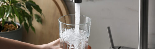 Homeowner filling glass from kitchen sink